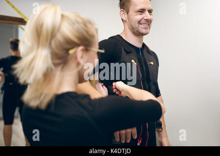 Portrait of happy man in ems suit and woman helping him putting it on Stock Photo