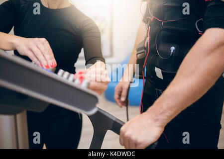 Close up cropped portrait of sportsman and trainer hands on ems device Stock Photo