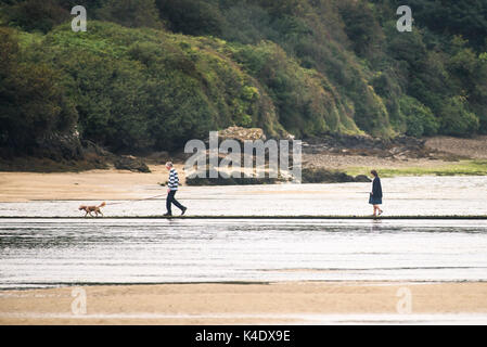 Gannel Estuary - a couple walking their pet dog on a footbridge over the Gannel River in Newquay, Cornwall. Stock Photo