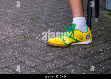 A left foot wearing a brightly coloured yellow Umbro trainer. Stock Photo