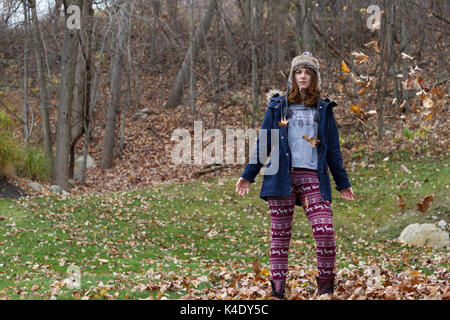 Autumn leaves falling on happy young woman in forest Stock Photo