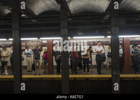 Workers wait for the B train at the 34th Street Subway Station in Manhattan, NYC. Stock Photo
