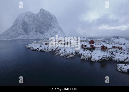 Hamnoy fishing hamlet near Reine village-heavy snowfall-red wooden rorbuer-traditional seasonal fishing huts-now for tourist use-foot of Festhaeltinde Stock Photo