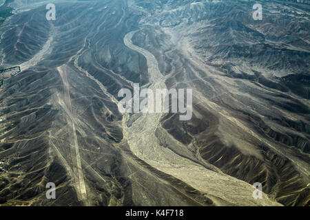 Palpa Lines (ancient geoglyphs) and dry riverbed in the desert near Nazca, Ica Region, Peru, South America - aerial Stock Photo