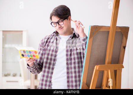 Young male artist drawing pictures in bright studio Stock Photo