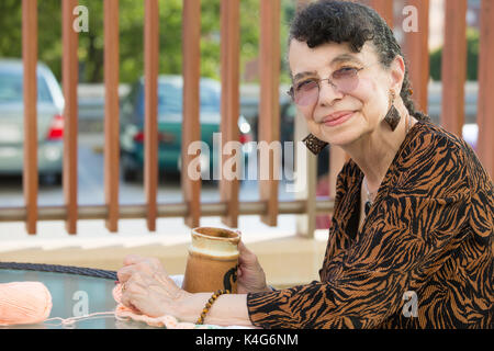 Closeup side view profile portrait, grandmother enjoying cup of drink, isolated outdoors background Stock Photo