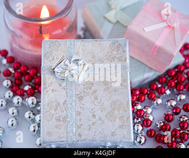 Small beautiful gift boxes with a candle decorated by beads on a white background.