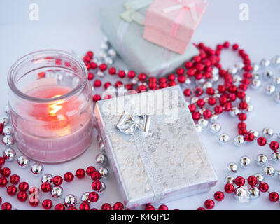 Small beautiful gift boxes with a candle decorated by beads on a white background. Stock Photo