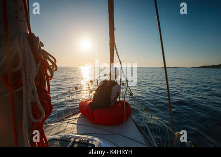 Young woman sitting on the bow of the yacht. Stock Photo