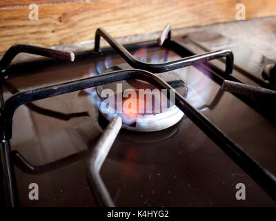 A small gas hob ring lights up with a blue flame Stock Photo