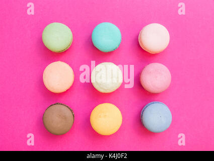 Sweet colorful French macaroon biscuits on bright fuchsia pink background Stock Photo