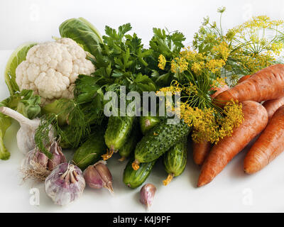 Vegetables of summer harvest, cauliflower, cucumbers, carrots, garlic, dill, parsley, dill inflorescences lie on a white background on a table Stock Photo