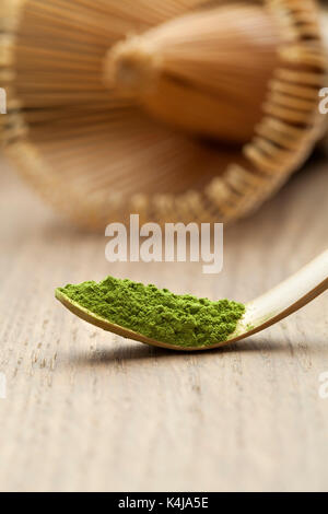Japanese bamboo matcha spoon, chashaku, with green tea and chasen on the background Stock Photo