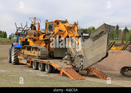 SALO, FINLAND - MAY 25, 2017: Inter-Drain 2028T trencher transported on a tractor trailer and other heavy equipment on a field work site where an agri Stock Photo