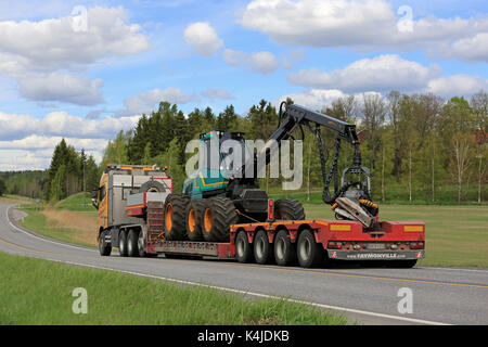 SALO, FINLAND - MAY 25, 2017: Yellow Volvo FH of Kosken Autokeskus transports Logman 811H forest harvester on gooseneck trailer along highway on a bea Stock Photo