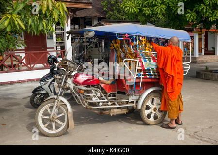 Monk standing near auto rickshaw, Luang Prabang, Laos Stock Photo