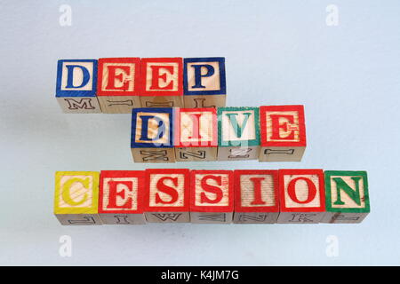 The term deep dive cession displayed visually on a white background using colorful wooden toy blocks in landscape format with copy space Stock Photo