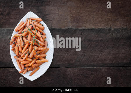 Honey Glazed Baby carrots and old wooden spoon. Image shot from above in flatlay style. Stock Photo