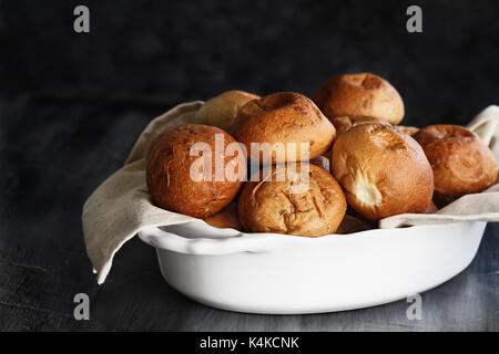 Fresh baked dinner rolls in a white dish ready for Thanksgiving Day against a rustic background. Extreme shallow depth of field with selective focus o Stock Photo