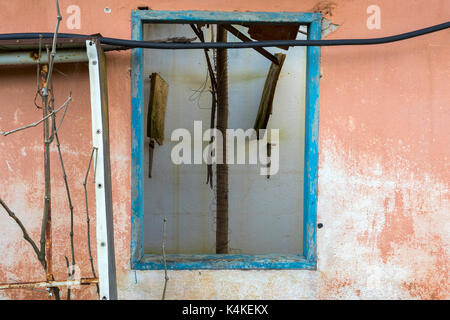 old wooden blue window frame on an orange wall of an abandoned house - horizontal Stock Photo