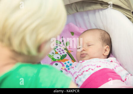 Mother looking at her newborn baby girl, who is laying in the stroller Stock Photo