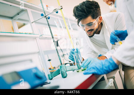 Young smiling student in white coat doing chemical tasks Stock Photo
