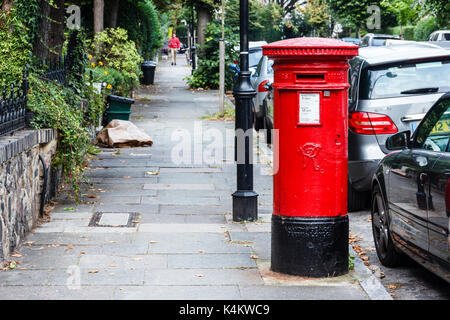 Traditional red  circular Victorian post box on a residential street in North London, UK Stock Photo