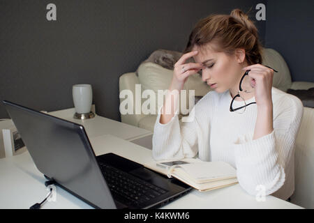 Student or freelancer, working at home with laptop. Feels tired Stock Photo