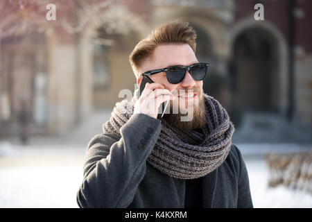 Man using phone and smiling, standing in winter city Stock Photo