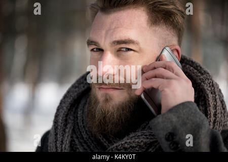 Close up of a man talking on the phone in forest during winter Stock Photo