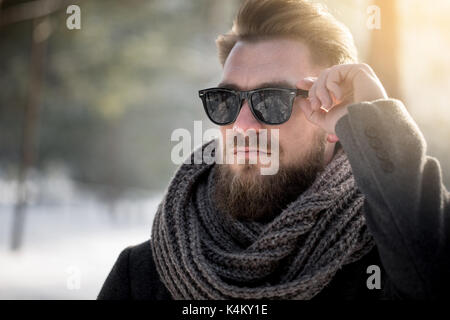 Man in sunglasses and winter coat standing in woods Stock Photo