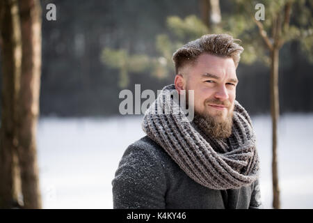 Man in winter clothes walking in snowy forest Stock Photo