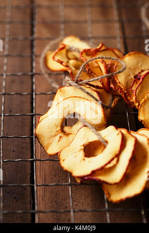 Dried apple slices hanging on string with dark metal backdrop Stock Photo