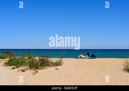 A lone woman relaxes in the sand among the dunes at Illinois Beach State Park at Zion, Illinois on the shore of Lake Michigan. USA. Stock Photo