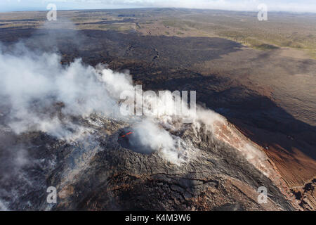 Aerial view of the smoking caldera and red molten lava of an active volcano on a mountaintop in Hawaii Stock Photo