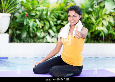 Fit woman showing thumb up during workout routine Stock Photo