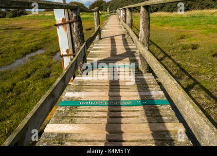 A Wooden footbridge over mudflats at high tide at Aberlady Bay local nature reserve, East Lothian coast, Scotland, UK Stock Photo