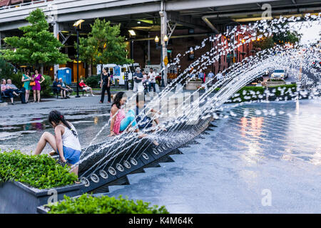 Washington DC, USA - August 4, 2017: Young children playing in water fountain in Georgetown park in evening with water splashing Stock Photo