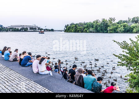 Washington DC, USA - August 4, 2017: People sitting in Georgetown park on riverfront in evening with potomac river Stock Photo