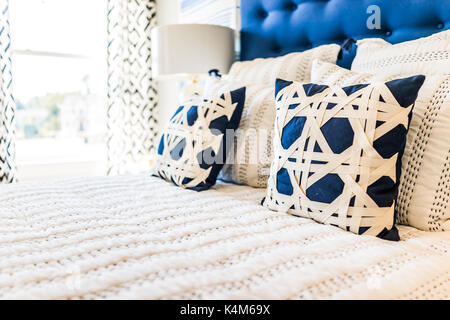 Closeup of new bed comforter with decorative pillows in bedroom in staging model home, house or apartment Stock Photo