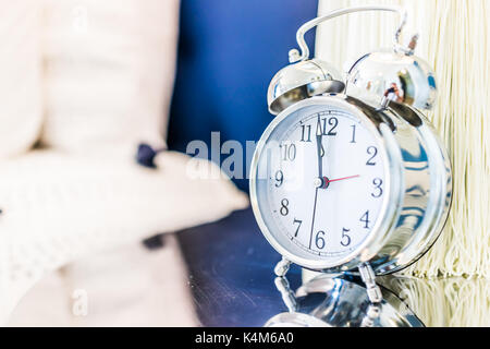 Closeup of modern vintage twin bell ring clock on desk or table nightstand by bed in staging model house, home or apartment Stock Photo