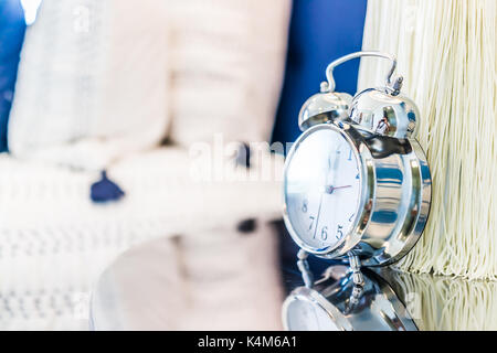 Closeup of modern vintage twin bell ring clock on desk or table nightstand by bed in staging model house, home or apartment Stock Photo