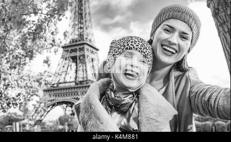 Autumn getaways in Paris with family. happy mother and child travellers on embankment near Eiffel tower in Paris, France taking selfie while sitting o Stock Photo