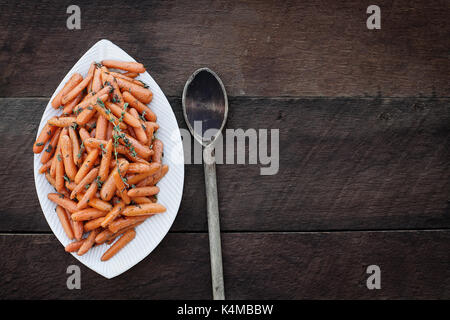 Honey Glazed Baby carrots and old wooden spoon. Image shot from above in flatlay style. Stock Photo