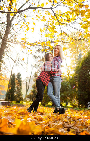 Happy mother hugging her teenage daughter posing in the sunlight Stock Photo