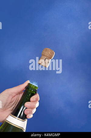 Champagne cork popping, high-speed image. The pressure of gas from the champagne has built up inside the bottle and caused the cork to pop out at high Stock Photo