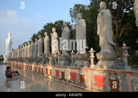 Woman praying in front of Buddha Amitabha statues, Dai Tong Lam Tu Buddhist Temple, Ba Ria, Vietnam, Indochina, Southeast Asia, Asia Stock Photo
