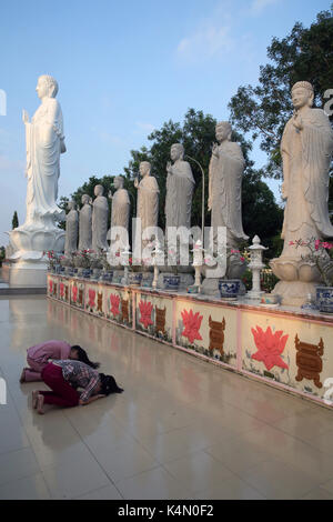 Woman praying in front of Buddha Amitabha statues, Dai Tong Lam Tu Buddhist Temple, Ba Ria, Vietnam, Indochina, Southeast Asia, Asia Stock Photo