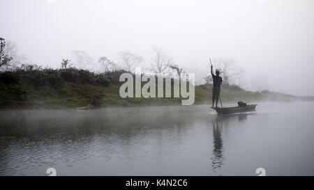 Reflection: man rowing on the boat in the foggy forest on the Narayani River in nepal, chitwan national park rain forest Stock Photo