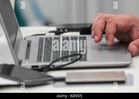 Businessman works with laptop and use smartphone on table, close up Stock Photo